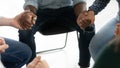 Multiethnic people sitting on chairs uniting hands in symbolic loop Royalty Free Stock Photo