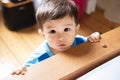 A multiethnic Southeast Asian and Spanish infant wearing blue pajamas looking at camera with an expression of surprise and a funny