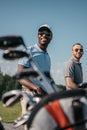 Multiethnic sportsmen going to the golf course, bag with clubs on foreground Royalty Free Stock Photo
