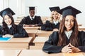 group of multiethnic students in graduation costumes sitting Royalty Free Stock Photo