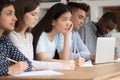 Multiethnic students listen to tutor make notes at lecture