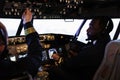 Multiethnic team of pilots using control panel in cockpit to fly airplane Royalty Free Stock Photo