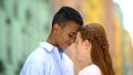 Multiethnic teen couple touching foreheads looking into eyes with love, romance