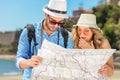 Multiethnic traveler couple using generic local map together on sunny day.