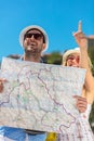 Multiethnic traveler couple using generic local map together on sunny day. Royalty Free Stock Photo