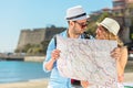 Multiethnic traveler couple using generic local map together on sunny day.