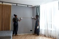 Multiethnic woman and man measuring wall to fit furniture Royalty Free Stock Photo