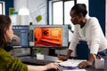 Multiethnic women designer looking at computer with dual displays