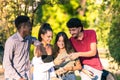 Multiethnic young people looking at a mobile phone while smiling outdoors Royalty Free Stock Photo
