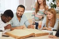 Multiethnic young people sitting at table reading reference books for study notes. Group of young students doing school Royalty Free Stock Photo