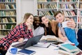 Multiethnical smiling happy students are studying in library, having fun during break and making selfie photo. Young Royalty Free Stock Photo