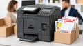 Multifunctional printer creating documents for publishing, printing, and office work, with cardboard boxes and blurred workers in Royalty Free Stock Photo