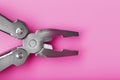 Multifunctional tool close-up on a pink background. The concept of a pocket tool with free space. Royalty Free Stock Photo