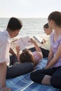Multigenerational family relaxing and reading on the beach Royalty Free Stock Photo