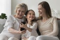 Multigenerational family spend leisure on internet using smart phone Royalty Free Stock Photo