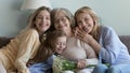 Multigenerational women look at camera posing at home with flowers