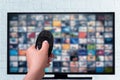 Multimedia streaming concept. female hand holds remote control. TV screen with lot of pictures. VoD content provider Royalty Free Stock Photo