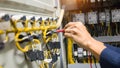 Electricians hands testing current electric in control panel