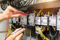 Electricians hands testing current electric in control panel