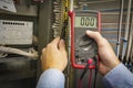 Multimeter in hands of electrician engineer closeup on electric panel background. Test circuit. Service work. Royalty Free Stock Photo