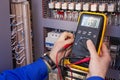 Multimeter in hands of electrician engineer in electrical cabinet. Maintenance of electric system Royalty Free Stock Photo
