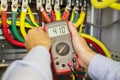 Multimeter in hands of electrician in power high voltage three phase circuit box close-up. Engineer hands with tester measured. Royalty Free Stock Photo