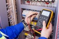 Multimeter is in hands of engineer in electrical cabinet. Adjustment of automated control system for industrial equipment