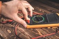 Multimeter and two test leads on a wooden background. A man`s hand holds two test leads. A studio photo with hard lighting Royalty Free Stock Photo