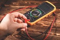 Multimeter and two test leads on a wooden background. A man`s hand holds two test leads. A studio photo with hard lighting Royalty Free Stock Photo