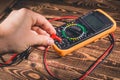 Multimeter and two test leads on a wooden background. A man`s hand holds two test leads. A studio photo with hard lighting Royalty Free Stock Photo