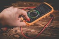 Multimeter and two test leads on a wooden background. A man`s hand holds two test leads. A studio photo with hard lighting Royalty Free Stock Photo