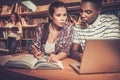 Multinational group of cheerful students studying in the university library. Royalty Free Stock Photo