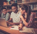 Multinational group of cheerful students studying in the university library. Royalty Free Stock Photo