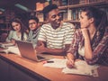 Multinational group of cheerful students studying in the university library. Royalty Free Stock Photo