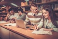 Multinational group of cheerful students studying in the university library.