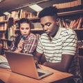 Multinational group of cheerful students studying in the university library. Royalty Free Stock Photo