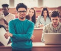 Multinational group of cheerful students taking an active part in a lesson while sitting in a lecture hall. Royalty Free Stock Photo