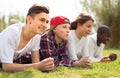 Multinational modern teens lie in the park on the grass Royalty Free Stock Photo