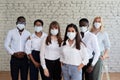 Multinational office workers stand in protective masks and look at the camera