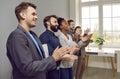 Multinational people working in same company applaud stand in office along wall
