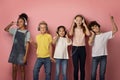 Multinational pupils in headsets enjoying music or listening to audio books over pink background