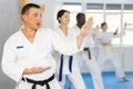 Multinational students repeat position and perform sequence of punches and painful techniques kata
