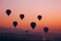 multiple balloons taking flight, pinkorange dawn sky