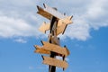 Blank wooden arrow signposts on wood pole agains blue sky