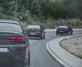 Multiple cars driving together in a column on a cold rainy day. Car enthusiast gathered and going for a road trip. Back view of a Royalty Free Stock Photo