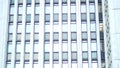 Multiple closed windows on a large, white blur office building, geometric background with lots of window rows. Many Royalty Free Stock Photo