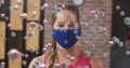 Multiple covid-19 cells floating against portrait of caucasian fit woman wearing a mask at the gym