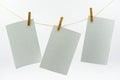 Multiple empty paper sheet for notes that hang on a rope with clothespins and isolated on white. Blank white photo hanging on rope Royalty Free Stock Photo