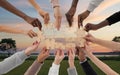Multiple hands of different skin tones reach out to connect wooden puzzle pieces, creating a sense of unity and collaboration
