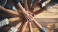 Multiple hands of different skin tones joining together in a teamwork gesture on a wooden surface Royalty Free Stock Photo